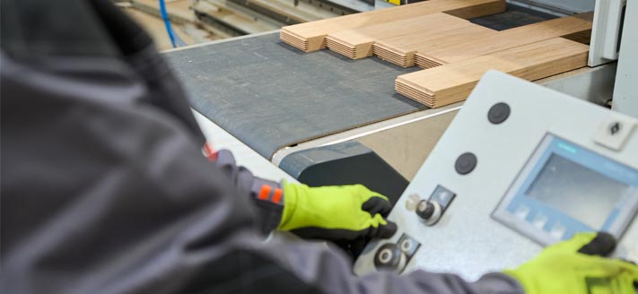 finger jointing process operator at control panel of specialized machine controls the cut of finger profiles